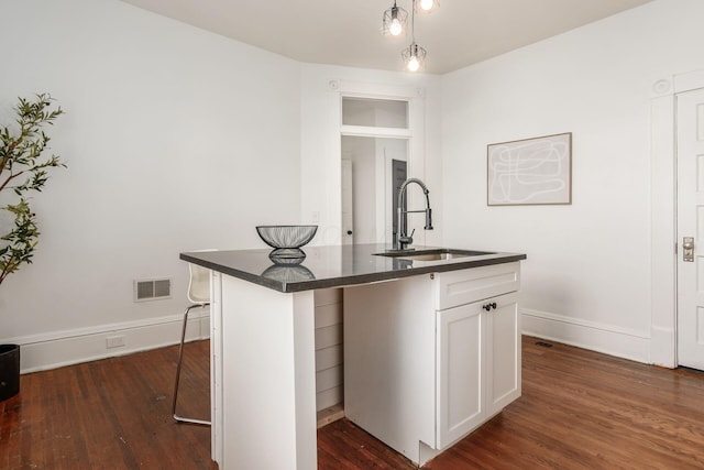 kitchen featuring white cabinetry, sink, a kitchen breakfast bar, and dark hardwood / wood-style floors