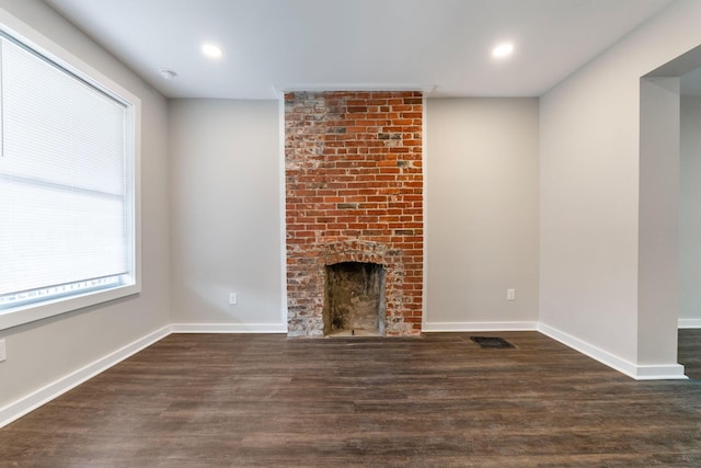 unfurnished living room featuring dark wood-type flooring and a fireplace