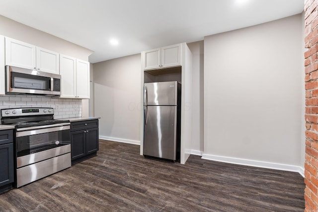 kitchen featuring brick wall, appliances with stainless steel finishes, backsplash, white cabinets, and dark hardwood / wood-style flooring