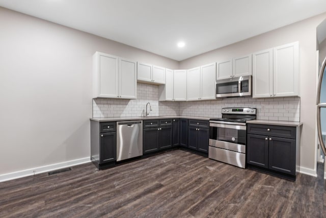 kitchen featuring sink, appliances with stainless steel finishes, white cabinetry, backsplash, and dark hardwood / wood-style flooring