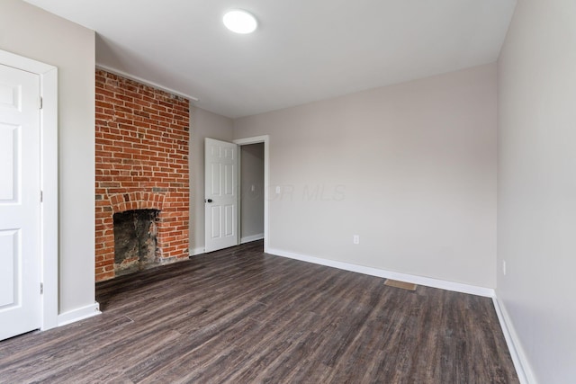 unfurnished living room featuring a brick fireplace and dark hardwood / wood-style floors