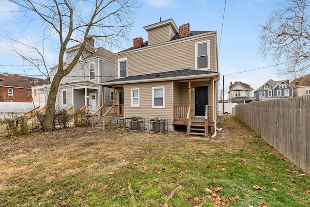 rear view of house featuring a lawn and central air condition unit