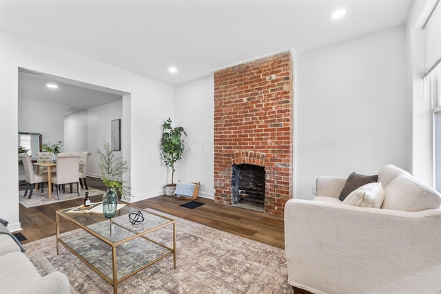 living room with a brick fireplace and wood-type flooring