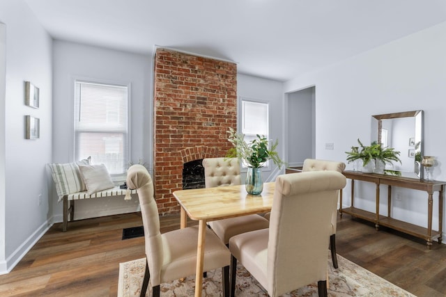 dining area featuring dark wood-type flooring and a fireplace