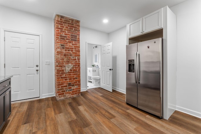 kitchen with stainless steel fridge, hardwood / wood-style floors, and white cabinets