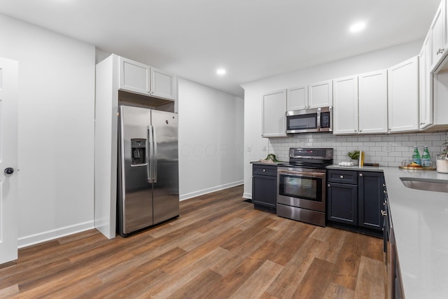 kitchen featuring white cabinetry, stainless steel appliances, dark wood-type flooring, and decorative backsplash