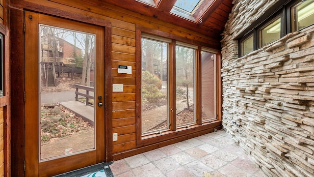 doorway with a skylight, wooden walls, and plenty of natural light