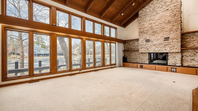 unfurnished living room with a healthy amount of sunlight, wood ceiling, beamed ceiling, and carpet flooring