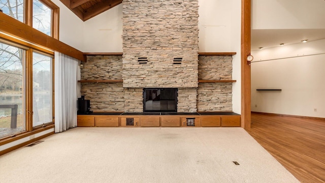 unfurnished living room featuring beam ceiling, wood-type flooring, high vaulted ceiling, and a fireplace