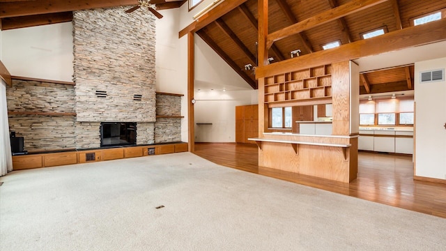 unfurnished living room with wood ceiling, high vaulted ceiling, ceiling fan, beam ceiling, and carpet