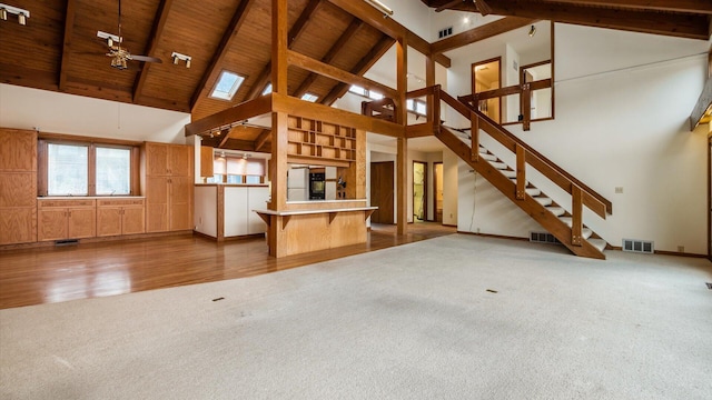 unfurnished living room featuring wood ceiling, ceiling fan, beam ceiling, and carpet