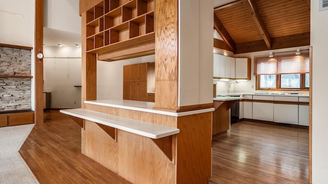 kitchen featuring vaulted ceiling with beams, a kitchen breakfast bar, white cabinets, kitchen peninsula, and light wood-type flooring