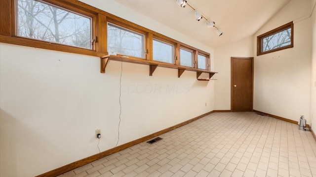 empty room with vaulted ceiling and track lighting