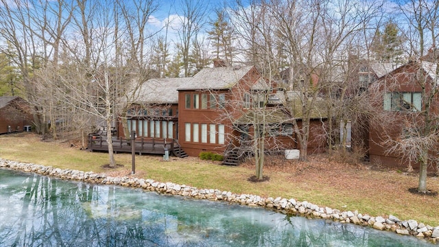 back of property featuring a deck with water view and a yard