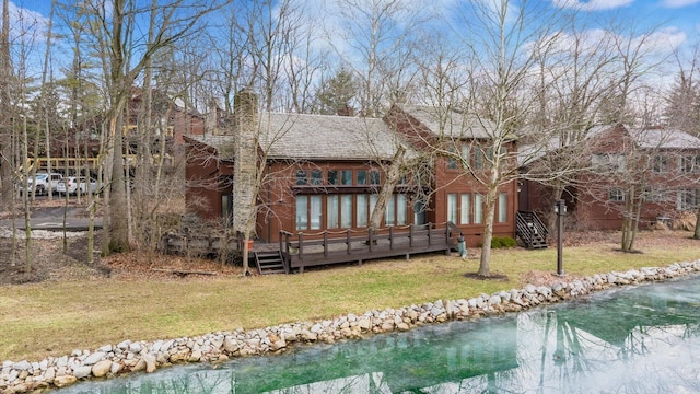 back of house featuring a deck with water view and a lawn