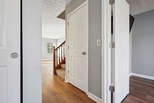 hall with wood-type flooring and a textured ceiling