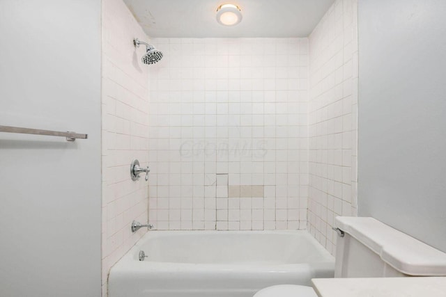 bathroom with tiled shower / bath combo and toilet