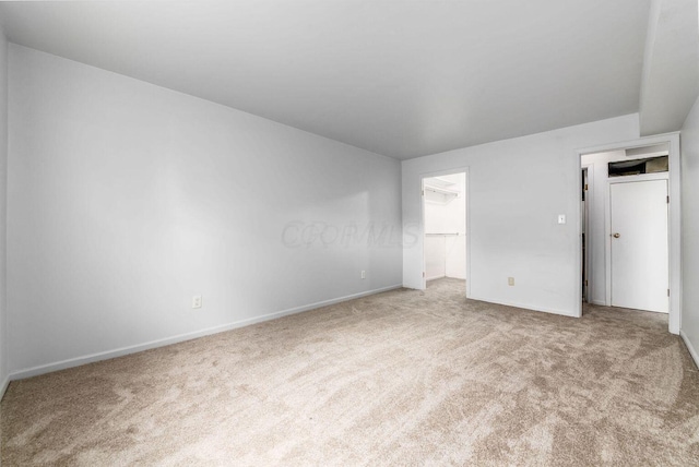 unfurnished bedroom featuring a walk in closet and light colored carpet