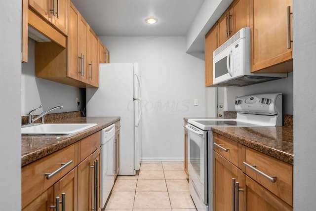 kitchen with white appliances, light tile patterned floors, sink, and dark stone counters