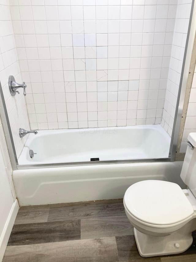 bathroom with toilet, hardwood / wood-style flooring, and tiled shower / bath combo