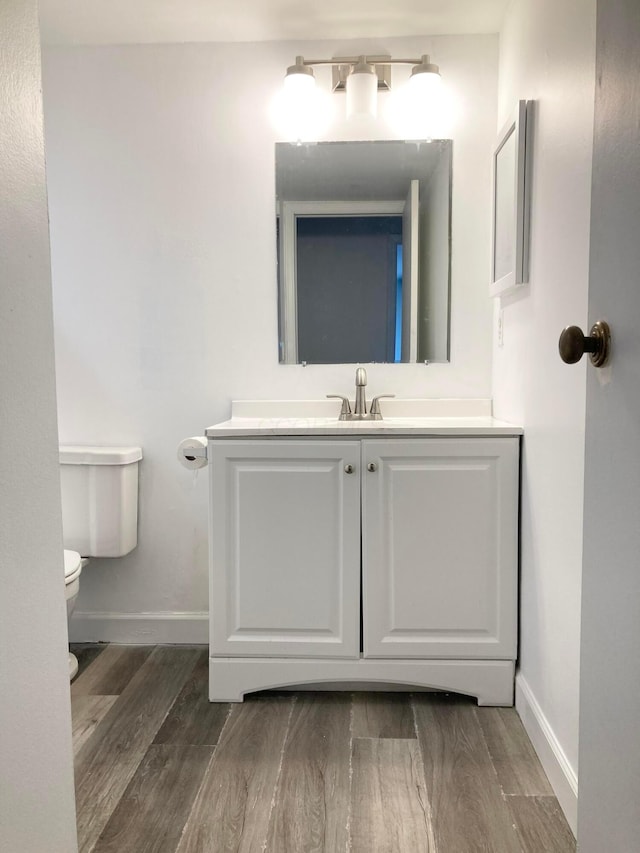 bathroom with hardwood / wood-style floors, toilet, and vanity