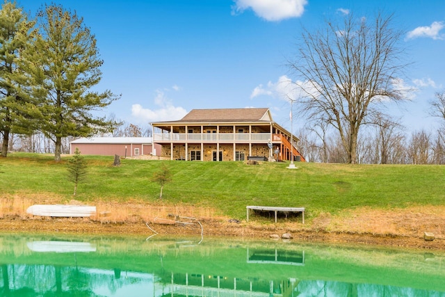 rear view of house featuring a deck with water view and a yard