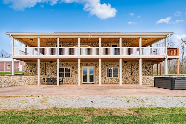 rear view of property with a hot tub, a deck, and a patio area