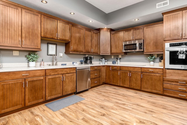 kitchen with stainless steel appliances, sink, and light hardwood / wood-style flooring