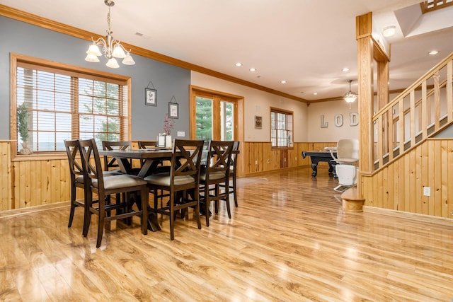 dining room featuring crown molding, wooden walls, a notable chandelier, and light wood-type flooring