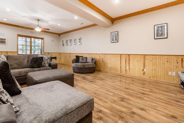 living room with hardwood / wood-style flooring, wooden walls, ornamental molding, and ceiling fan