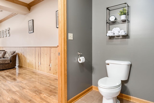 bathroom featuring hardwood / wood-style flooring, ornamental molding, toilet, and wood walls