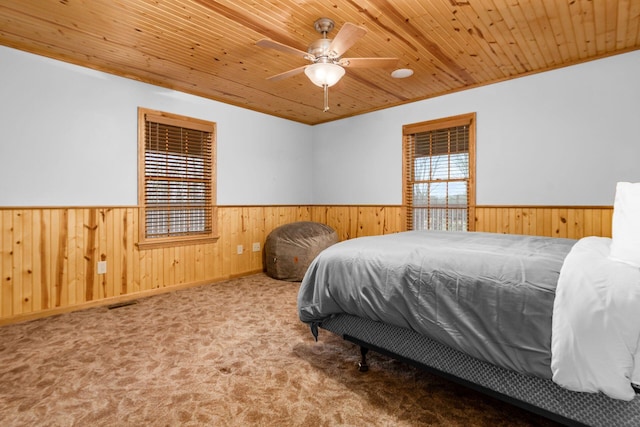 carpeted bedroom featuring wood ceiling, ornamental molding, and wood walls