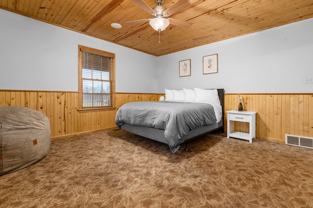 carpeted bedroom featuring wood ceiling and wooden walls