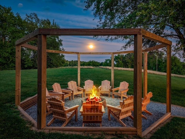 patio terrace at dusk with a yard, a water view, and an outdoor fire pit