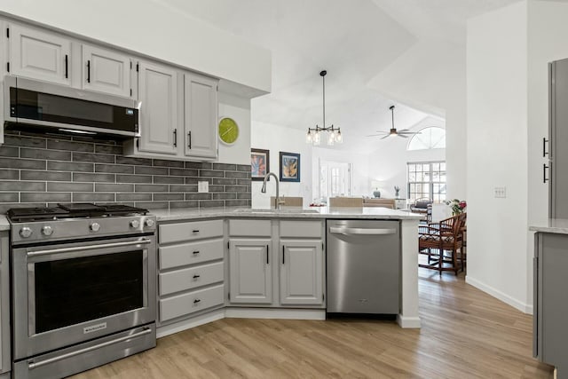 kitchen featuring sink, light hardwood / wood-style flooring, gray cabinets, appliances with stainless steel finishes, and backsplash