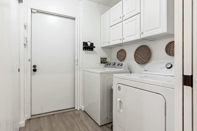 washroom featuring cabinets, light hardwood / wood-style flooring, and washer and dryer