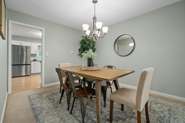 carpeted dining area featuring a textured ceiling and an inviting chandelier