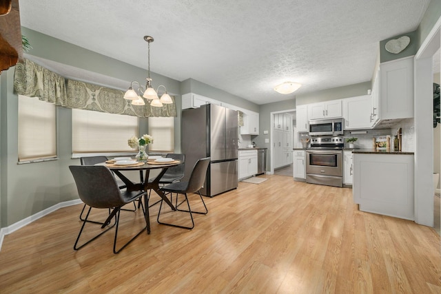 dining space featuring a notable chandelier, light hardwood / wood-style flooring, and a textured ceiling