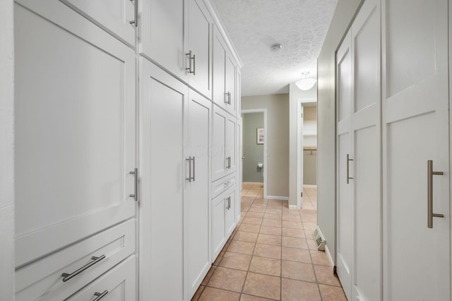 hallway with light tile patterned floors and a textured ceiling