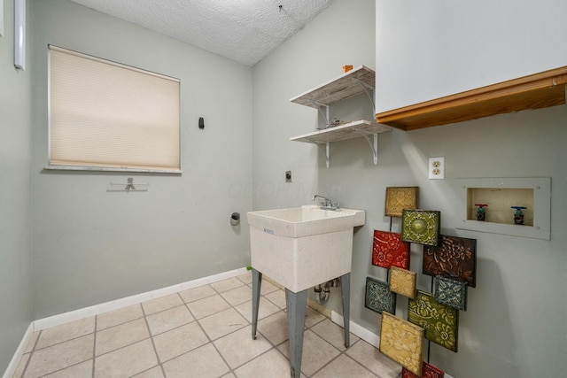 laundry area with sink, electric dryer hookup, washer hookup, a textured ceiling, and light tile patterned flooring