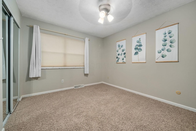 unfurnished bedroom with ceiling fan, carpet floors, a closet, and a textured ceiling