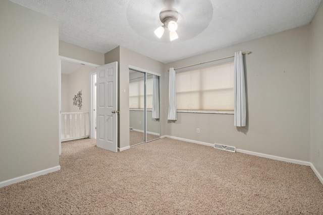 unfurnished bedroom featuring ceiling fan, carpet, a textured ceiling, and a closet