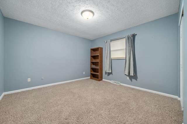 carpeted empty room with a textured ceiling