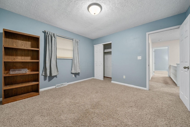 unfurnished bedroom featuring light colored carpet, a closet, and a textured ceiling