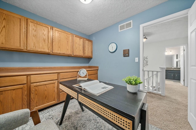 carpeted office featuring a textured ceiling