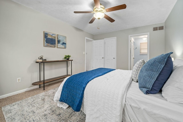 carpeted bedroom with ceiling fan, ensuite bathroom, and a textured ceiling