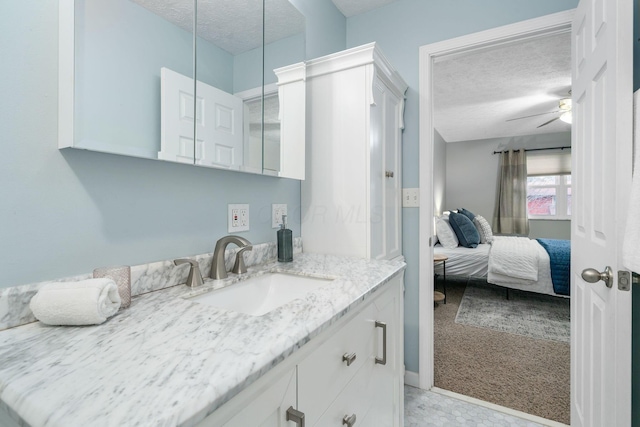 bathroom with ceiling fan, vanity, and a textured ceiling