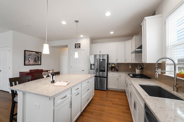 kitchen with sink, black appliances, white cabinets, a kitchen island, and decorative light fixtures