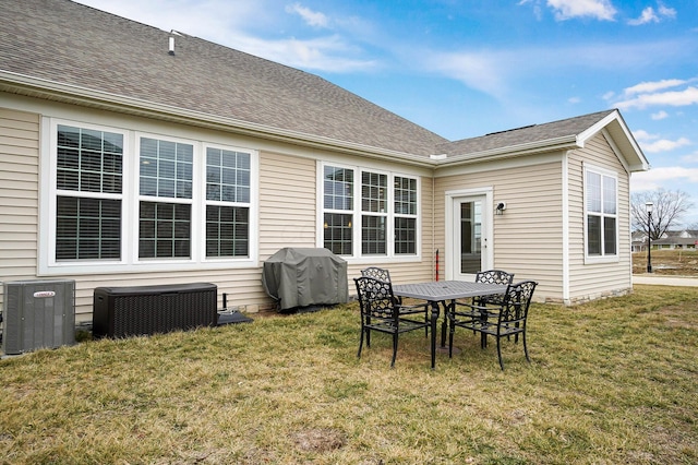 rear view of house featuring central AC unit and a lawn