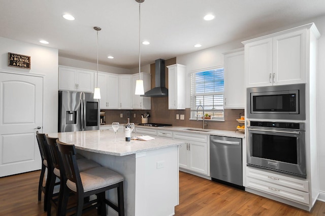 kitchen featuring stainless steel appliances, sink, wall chimney range hood, and white cabinets